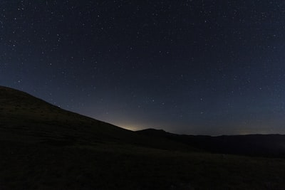 山的轮廓在夜间在蓝色的天空下
